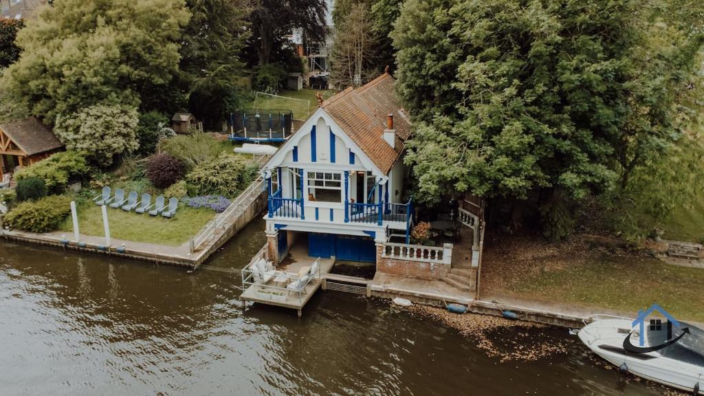 a blue house on the water next to a river at Unique Boathouse, detached free parking x4 cars in Kingston upon Thames