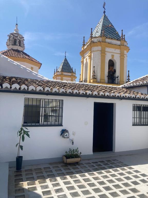 a white building with a black door and a tower at Apartamento Socorro in Ronda