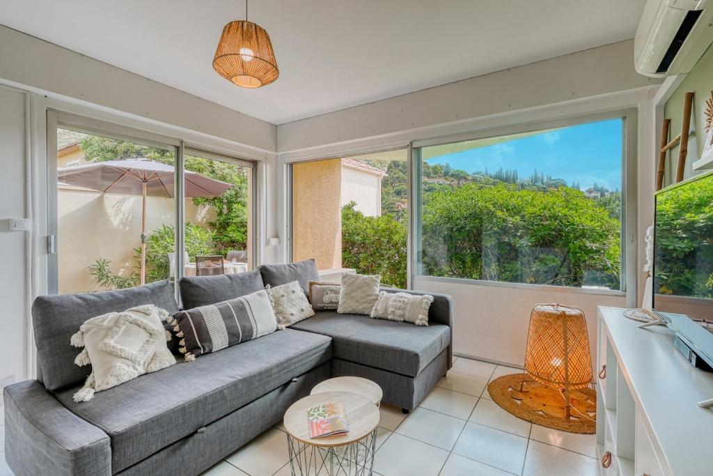 - un salon avec un canapé gris et de grandes fenêtres dans l'établissement Appartement La Fossette , 4 personnes, 5mn de la plage, WIFI, climatisation, parking, terrasse sans vis-à-vis, au Lavandou