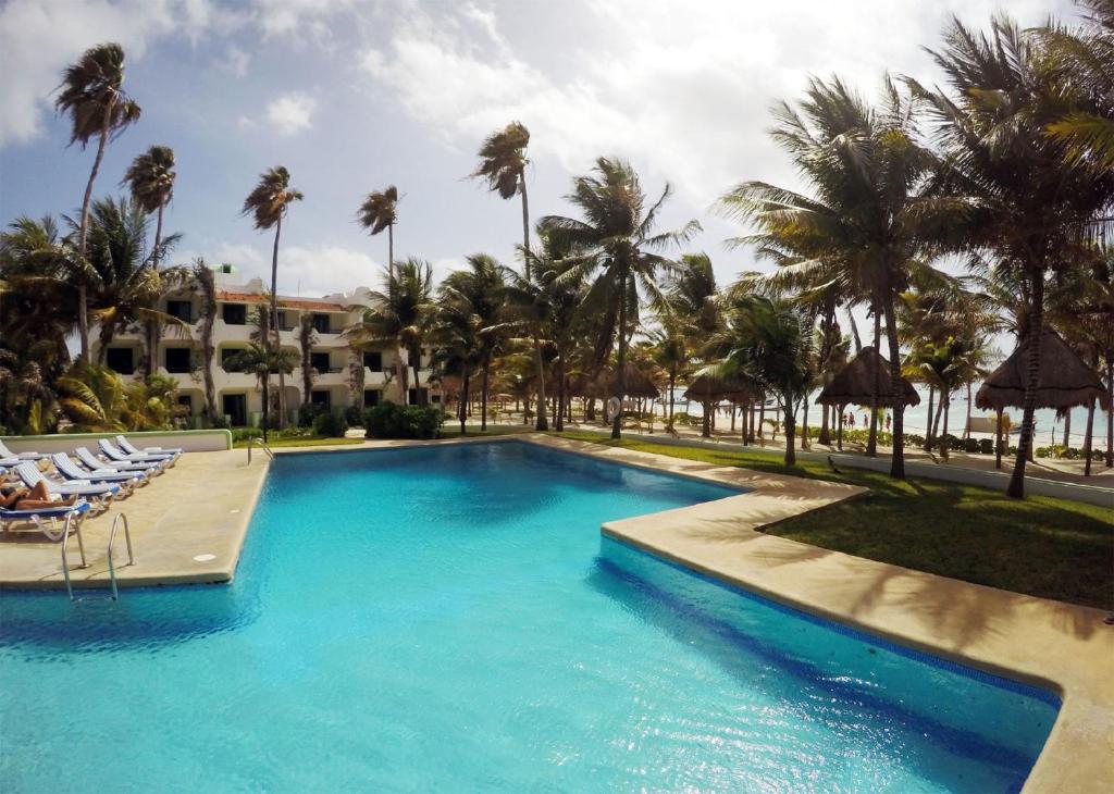 - une piscine bordée de chaises et de palmiers dans l'établissement Hotel Club Akumal Caribe, à Akumal