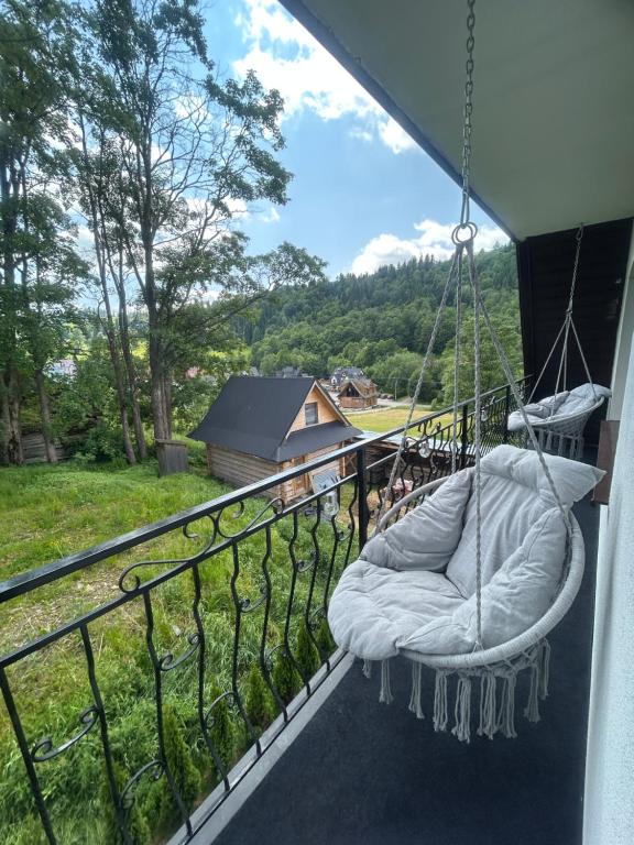 a swing on a balcony with a view of a house at Apartament Hey Gron in Groń