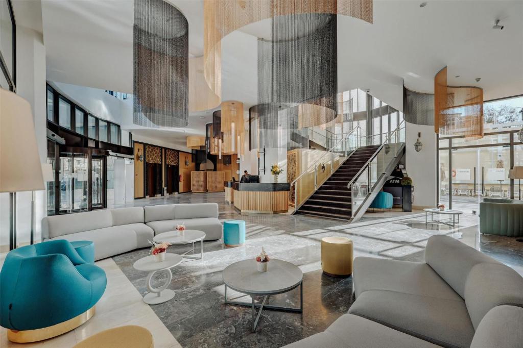un hall avec des canapés, des tables et un escalier dans l'établissement Barceló Fès Medina, à Fès