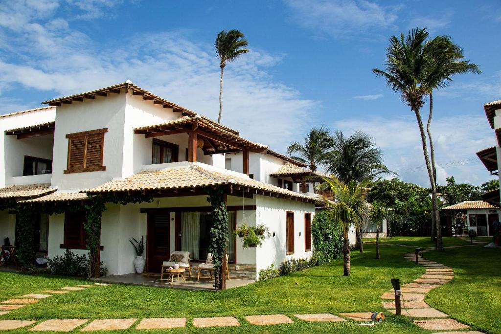 ein weißes Haus mit Palmen im Hof in der Unterkunft Casa Cajú in Cruz