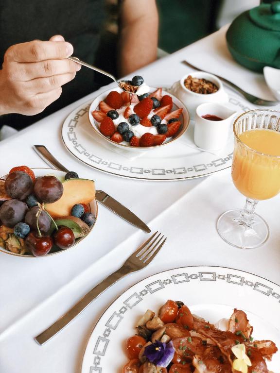 a table with plates of food and a person eating at Hotel Van Cleef in Bruges
