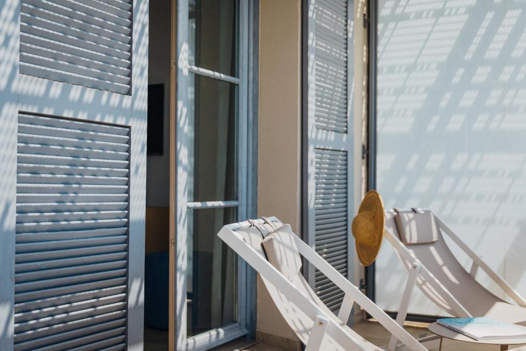 a couple of white chairs sitting in front of a window at Hôtel La Villa Douce in Rayol-Canadel-sur-Mer