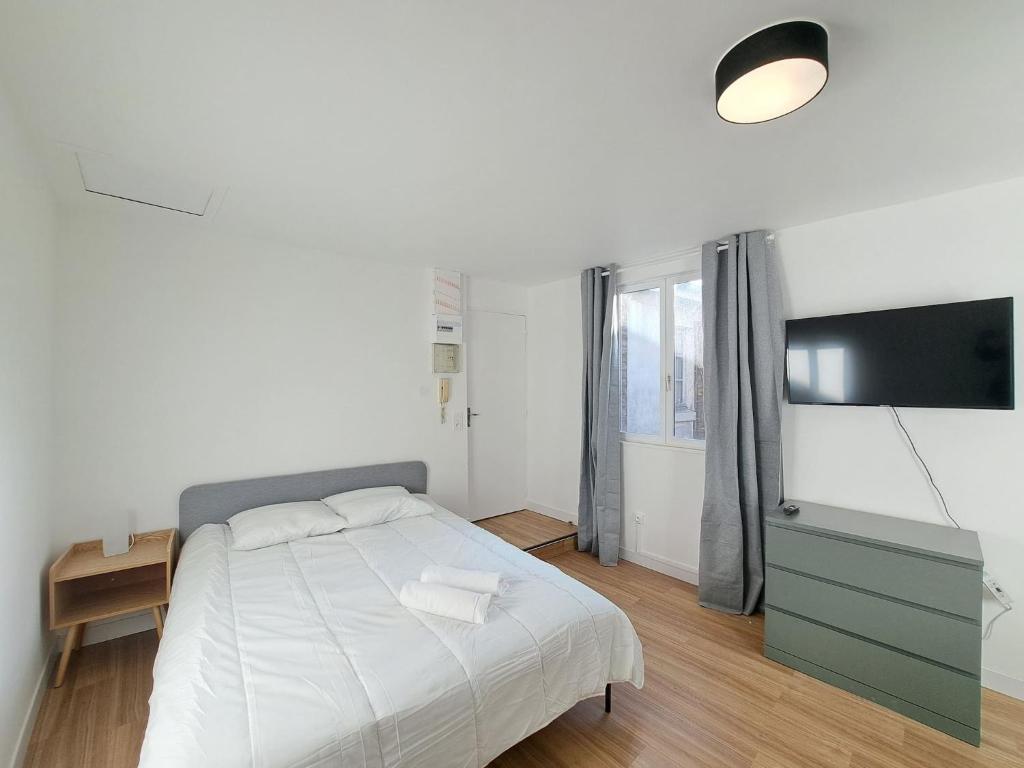 une chambre blanche avec un lit et une télévision à écran plat dans l'établissement Florence - Appart'city, à Reims