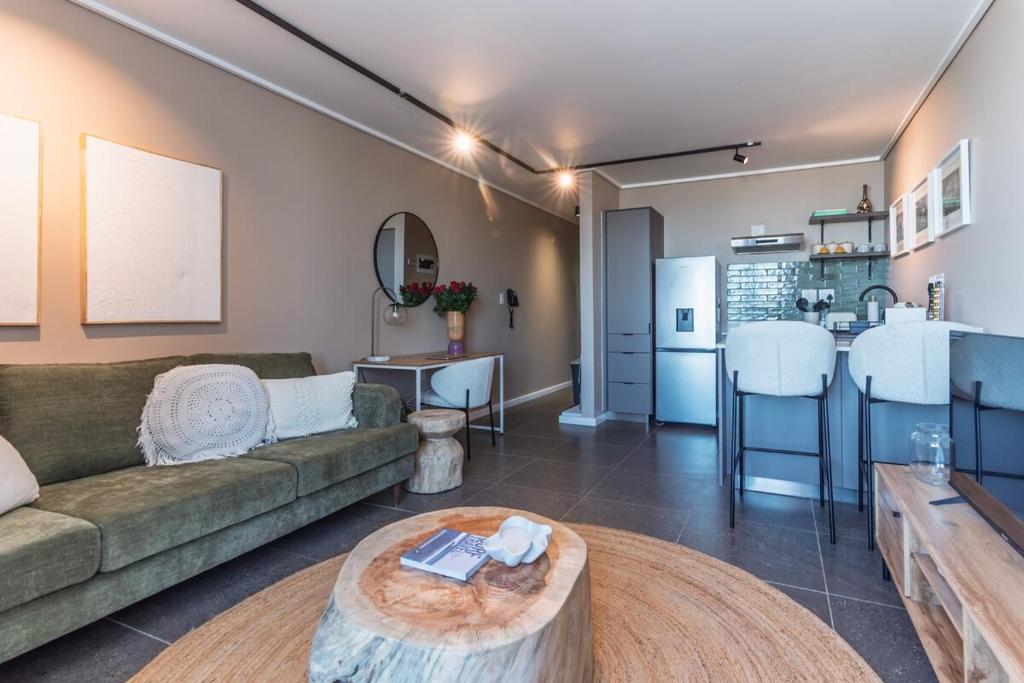 a living room with a couch and a table at Modern One Bedroom Wavescapes Apartment Muizenberg in Muizenberg