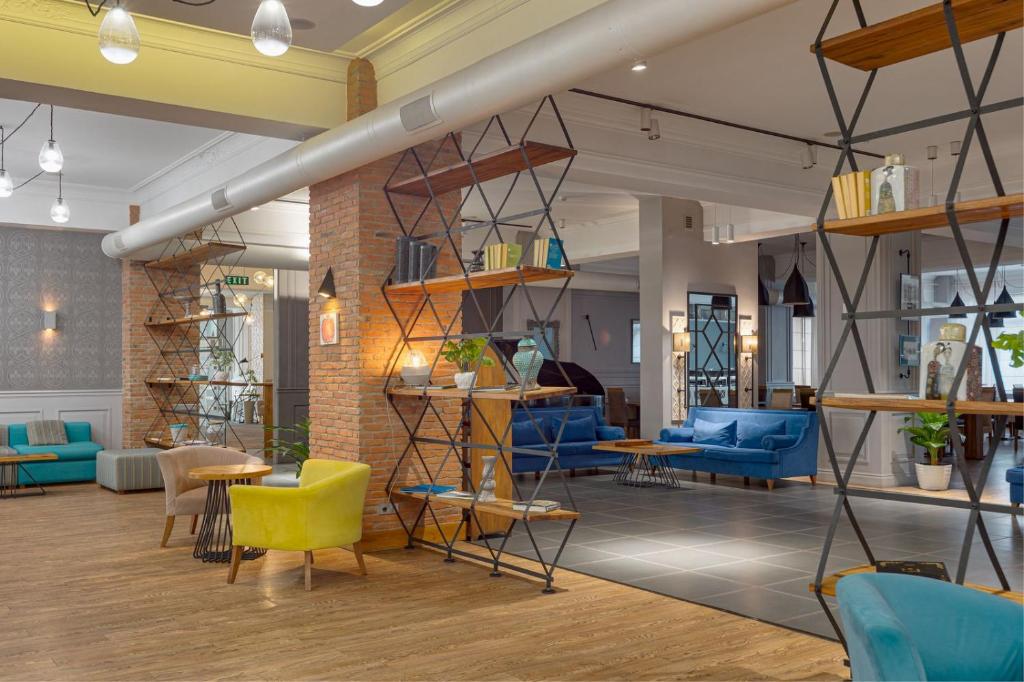 a lobby with blue and yellow chairs and tables at Hotel Mevora in Tbilisi City