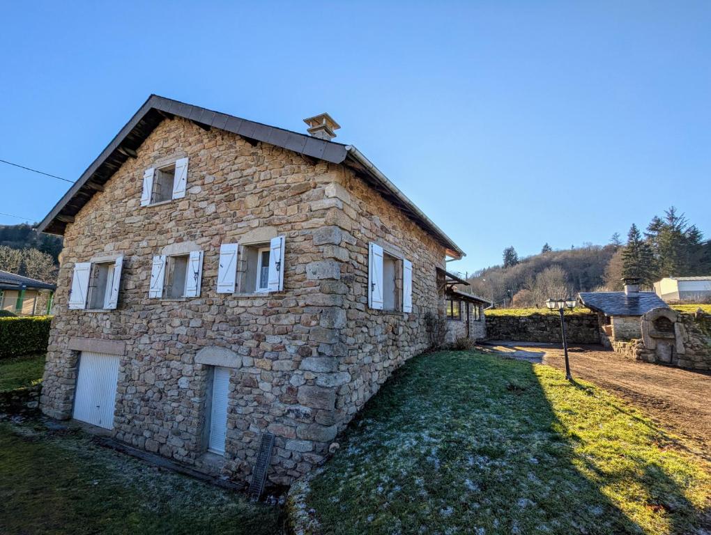 une maison en pierre au milieu d'une cour dans l'établissement La Bergerie Maison familiale, à La Salvetat-sur-Agout