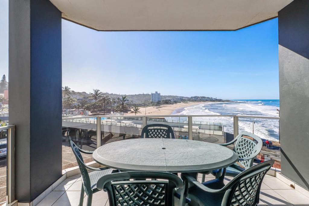 a balcony with a table and chairs and the beach at Seagull 302 in Margate