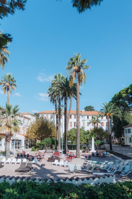 une terrasse avec des chaises et des palmiers devant un bâtiment dans l'établissement Campus Santa Maria, à Cannes
