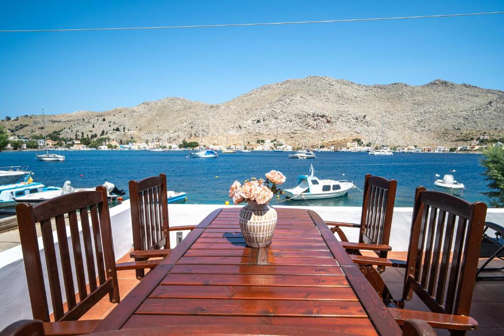 a wooden table with a vase of flowers sitting on it at Mythos House - Seaside Retreat in Pedi in Symi