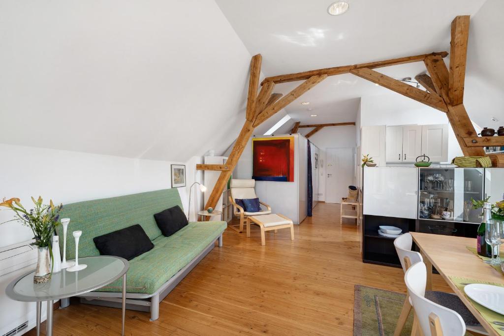 a living room with a green couch and a table at Atelierblick im Winzerort in Oberbergen