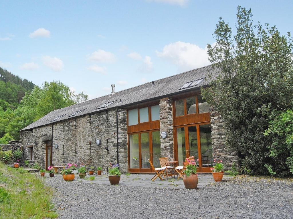 Una casa de piedra con una mesa y sillas delante de ella. en Hendre Barn Mawr, en Abergynolwyn
