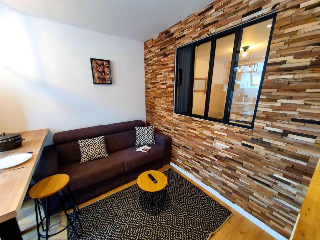 un salon avec un canapé et un mur de briques dans l'établissement L'ATELIER I Neuf I Parking Gratuit I Proche Mer, à Saint-Brieuc