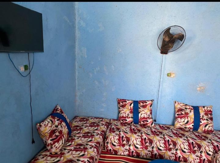 1 dormitorio con 1 cama con almohadas y ventilador en Housse stander merzouga, en Merzouga