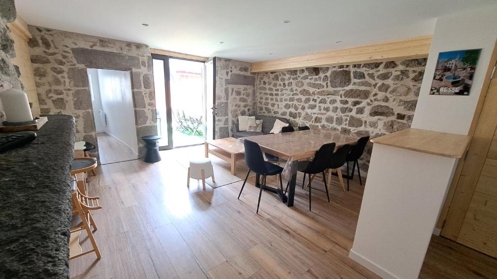 Cette chambre est dotée d'une table, de chaises et d'un mur en pierre. dans l'établissement Gite du B-ffroy - Besse et St Ansataise, à Besse-et-Saint-Anastaise
