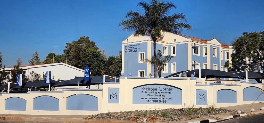 a white building with a palm tree in front of it at Melrose Corner Self-Catering Hotel Apartments in Johannesburg