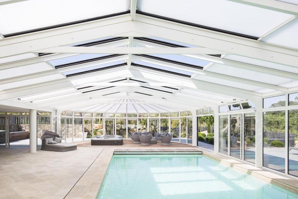 une piscine intérieure dans une véranda avec un plafond blanc dans l'établissement Grande maison en campagne avec piscine, 11 voyageurs, à Hénansal