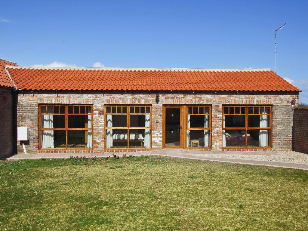 a brick building with large windows and a yard at Ploughman's Cottage in Flamborough