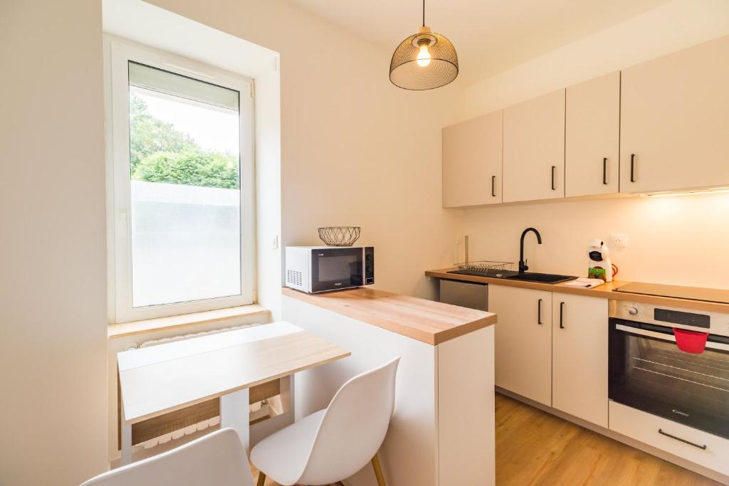 une cuisine avec des armoires blanches et une fenêtre dans l'établissement Studio pratique & cosy - centre de Guingamp, à Guingamp