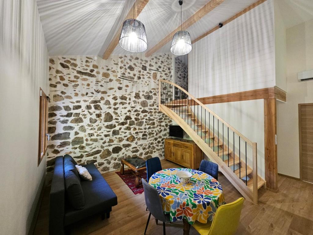 Saint-Jean-de-BuègesにあるLes mûriers de Roseのテーブルと石の壁のあるリビングルーム