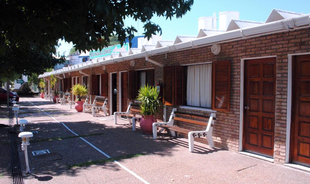 eine Reihe von Bänken vor einem Backsteingebäude in der Unterkunft Bungalows Archi in Termas del Daymán