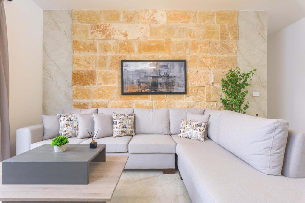 a white couch in a living room with a brick wall at Glow - Stylish Apartments & Rooftops in Batroun in Kubbā