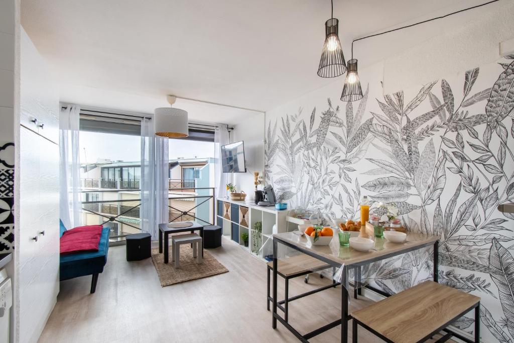 un salon avec une table et une fresque murale. dans l'établissement Studio cabine cosy Lagon Bleu Piscine, clim, parking, wifi inclus, au Grau-du-Roi