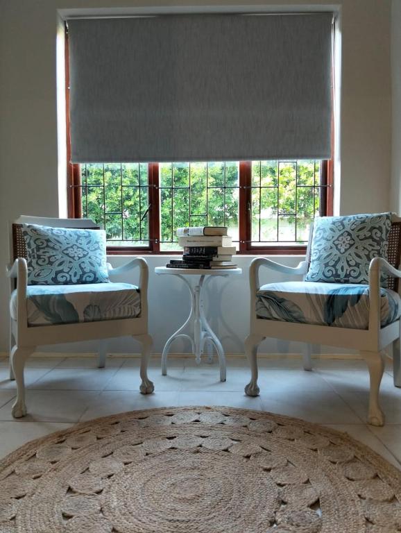 two chairs and a table in a room with a window at Charming Cottage in Prime Location in Gqeberha