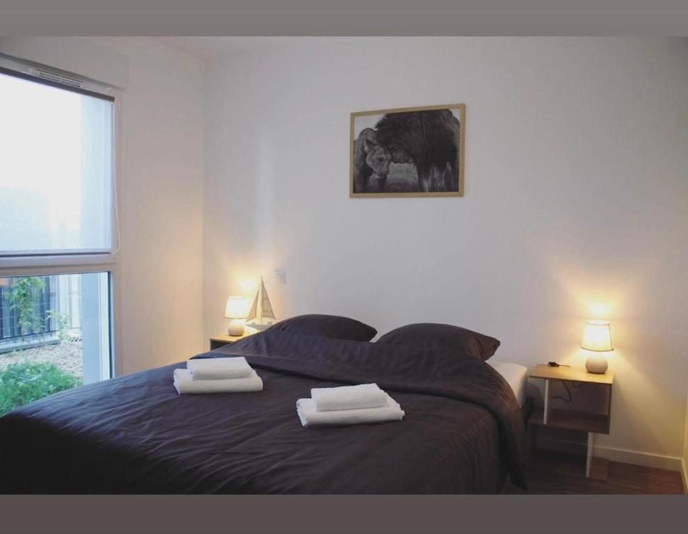 une chambre avec un lit avec deux serviettes dessus dans l'établissement T2 Cosy avec Terrasse et Jardinet, à La Rochelle