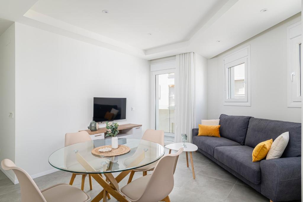 a living room with a blue couch and a glass table at Apartamento Vidamar 1 in Conil de la Frontera