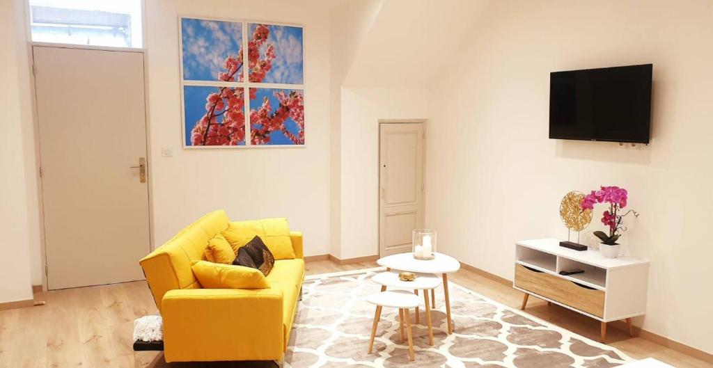 a living room with a yellow couch and a tv at maison ville st aff in Saint-Affrique