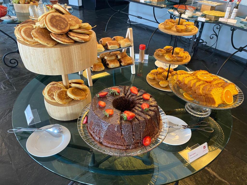 uma mesa de vidro coberta com um bolo de chocolate e outros doces em Luna Hotel dos Carqueijais - Serra da Estrela na Covilh
