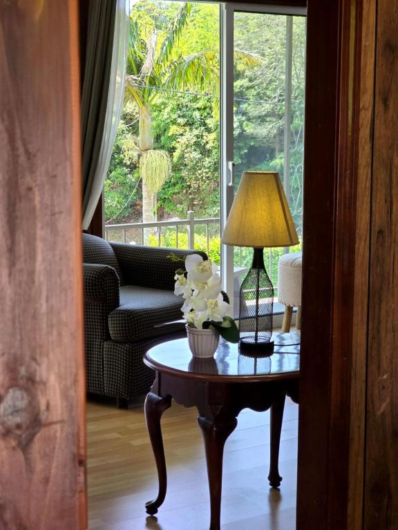 a living room with a table with a lamp and flowers on it at Encanto das Caldeiras in Furnas