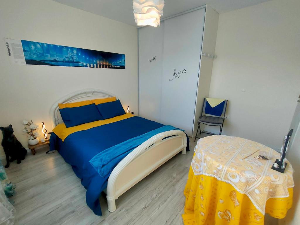 - une chambre avec un lit bleu et jaune et une table dans l'établissement BRETAGNE Chambre sur la Côte d'Émeraude Saint-Malo, à Saint-Guinoux