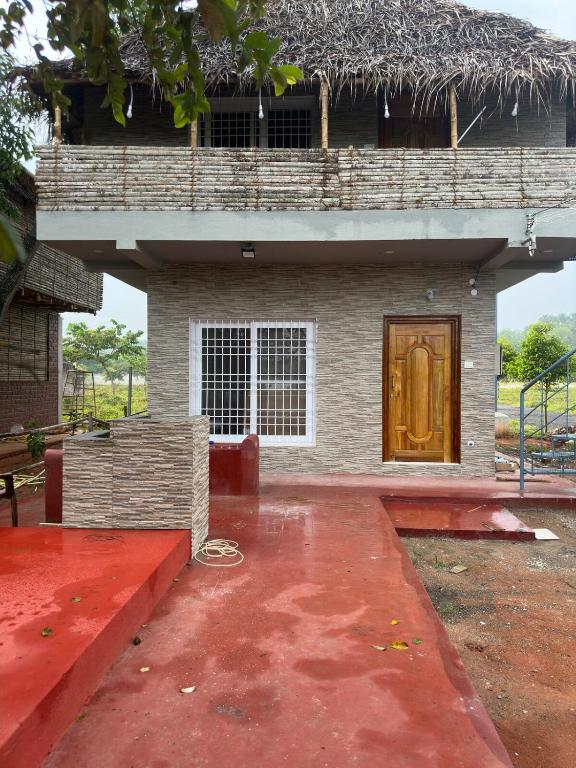 a building with a brown door and a red floor at Woodside Haven Luxury GF in Auroville