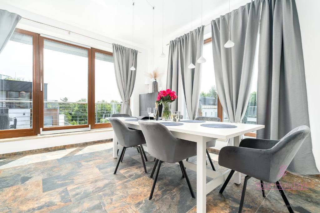 a white dining room with a white table and chairs at Your Holidays Golden Tulip in Międzyzdroje