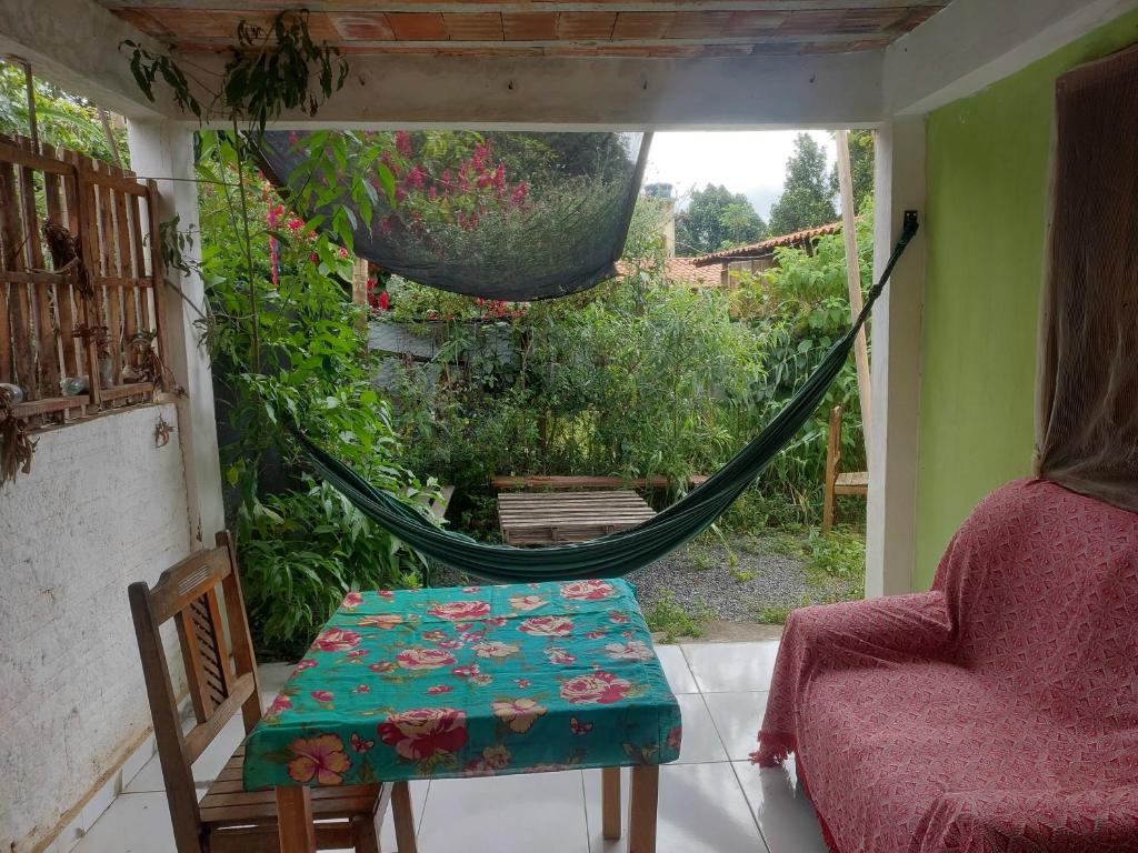 une pièce avec un hamac, une table et une chaise dans l'établissement Casa na Vila, à Vale do Capão