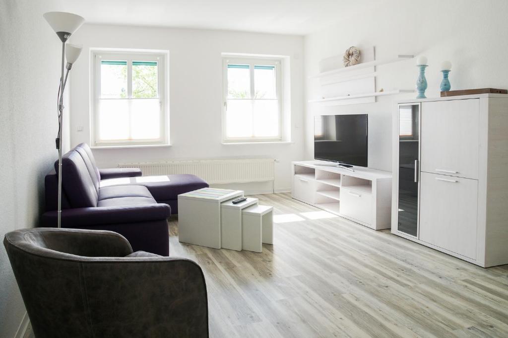 a white living room with a couch and a chair at Apartmenthaus Eldena in Greifswald