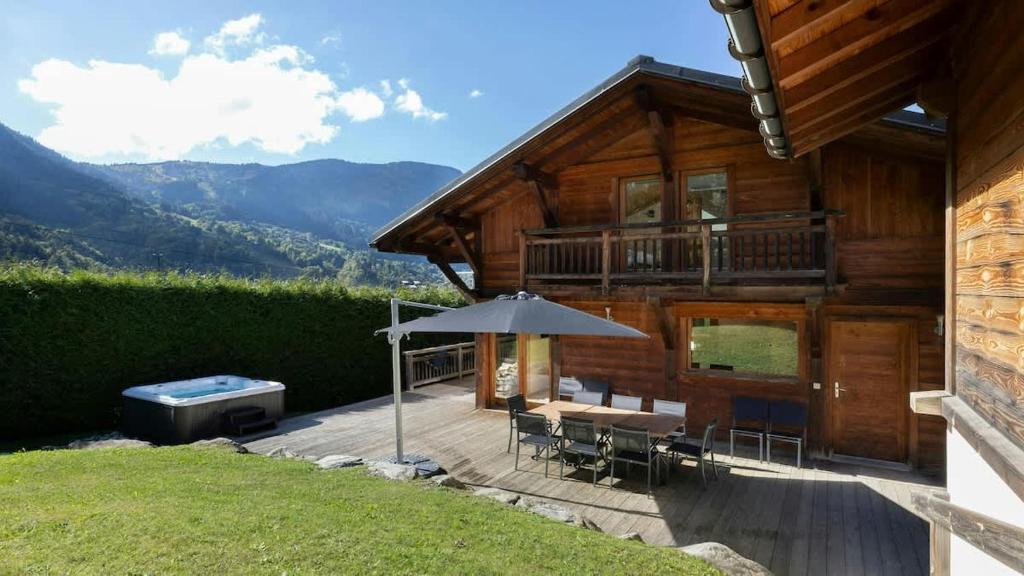 a wooden house with a deck with an umbrella at Family Chalet 5 bdr 5 bath Games Room Jacuzzi in Les Houches