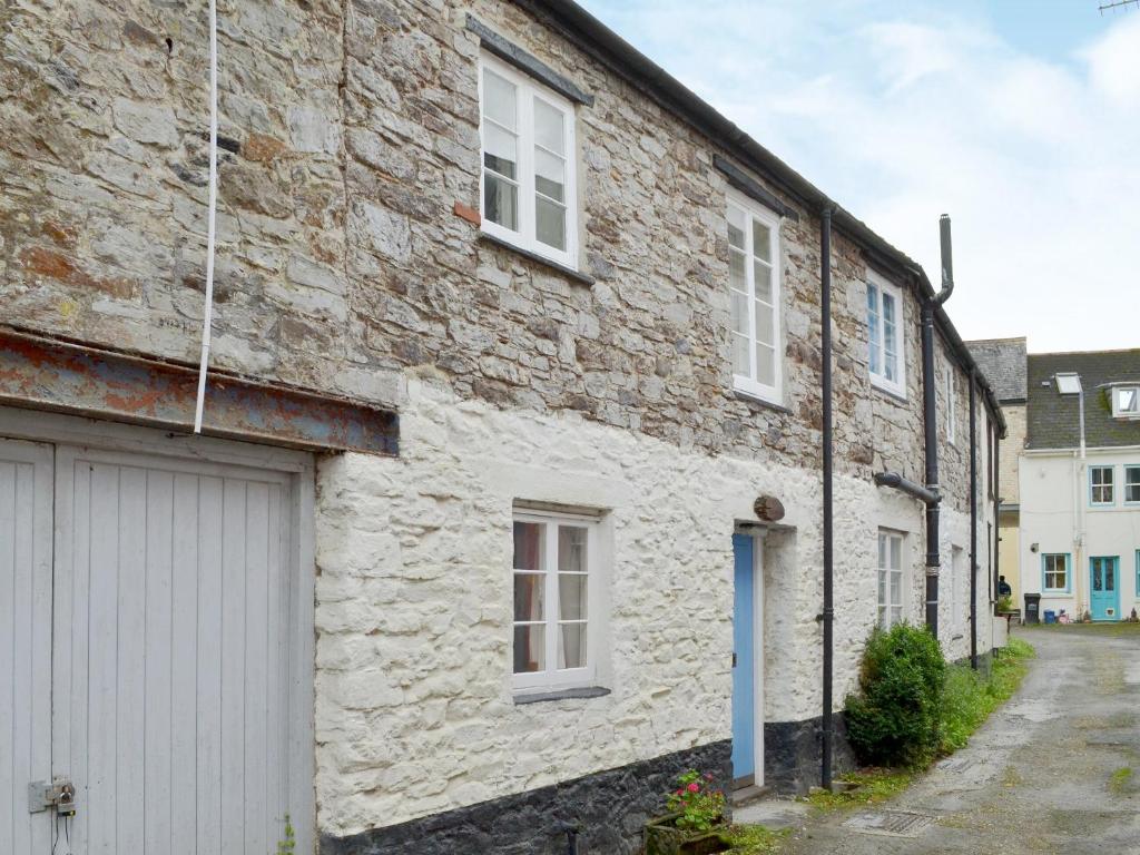 an old stone house with a garage on a street at Mill Cottage in Buckfastleigh