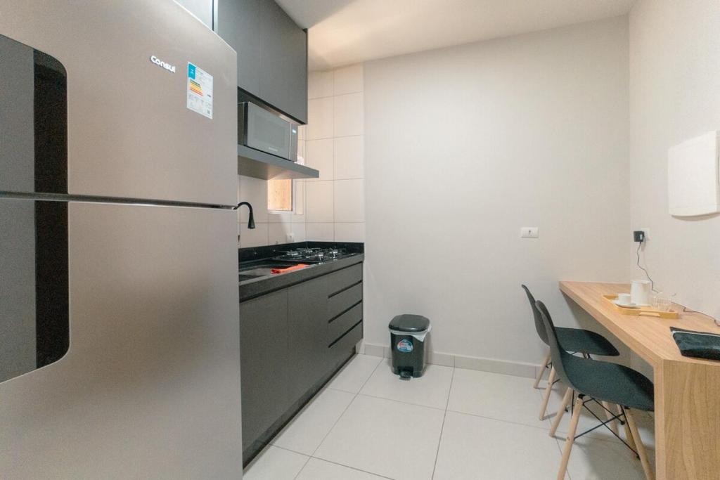 a kitchen with a refrigerator and a table with chairs at Apartamento Confortável - MEL402 in Maringá