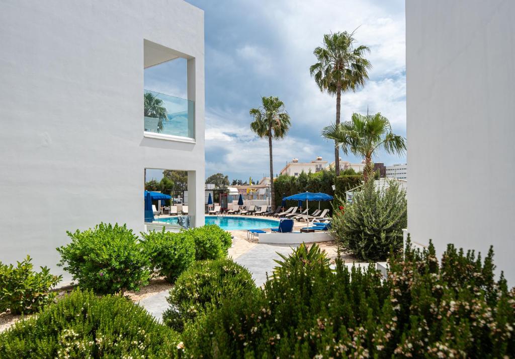 a white building with a swimming pool and palm trees at Bellini Hotel in Ayia Napa