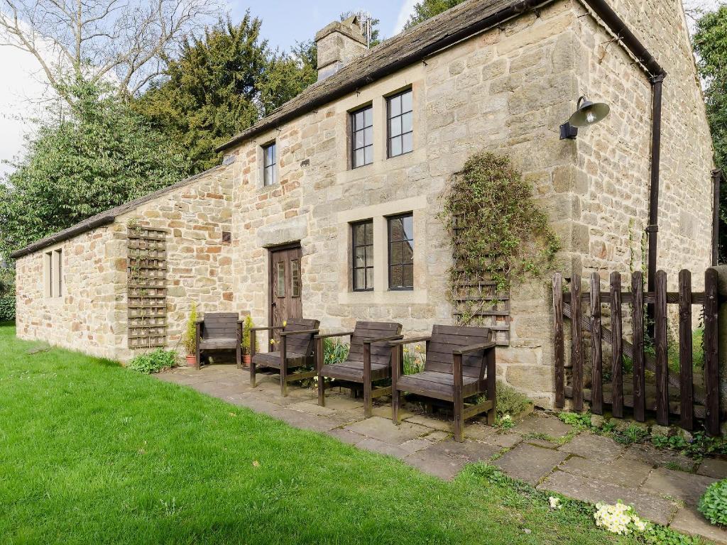 une vieille maison en pierre avec des chaises en bois et une table dans l'établissement Highbury Cottage, à Hathersage