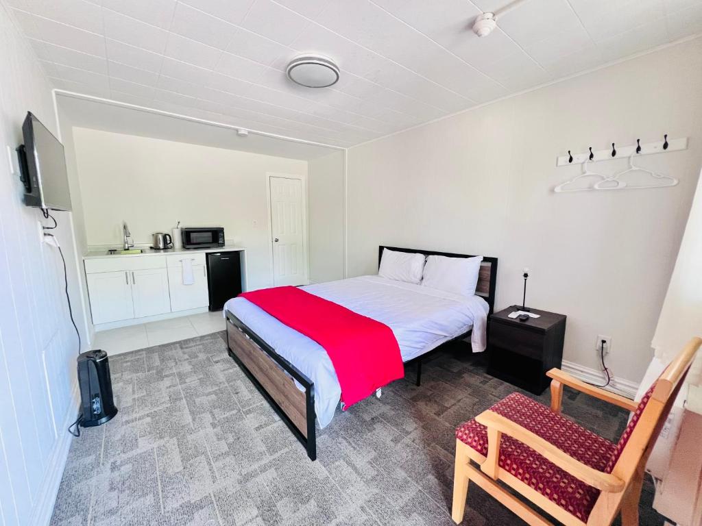 a bedroom with a bed with a red blanket and a chair at 6267 Persepolis Inn in Niagara Falls