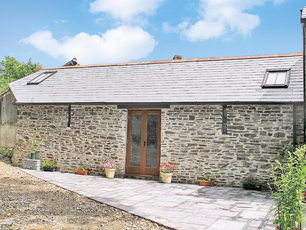 a stone building with a wooden door and aphaltphaltphalt at Lower Shippen - 23493 in North Petherwin
