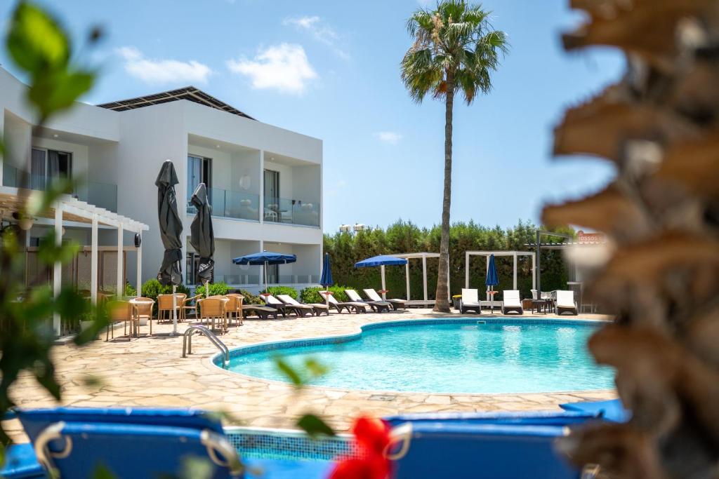 a pool with chairs and umbrellas and a building at Bellini Hotel in Ayia Napa