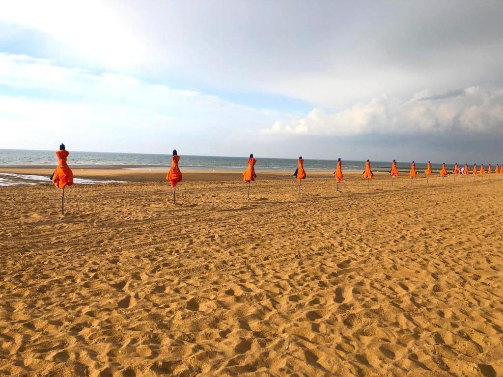 un groupe de personnes en orange sur une plage dans l'établissement Appartement de charme à 250m de la plage, à Houlgate