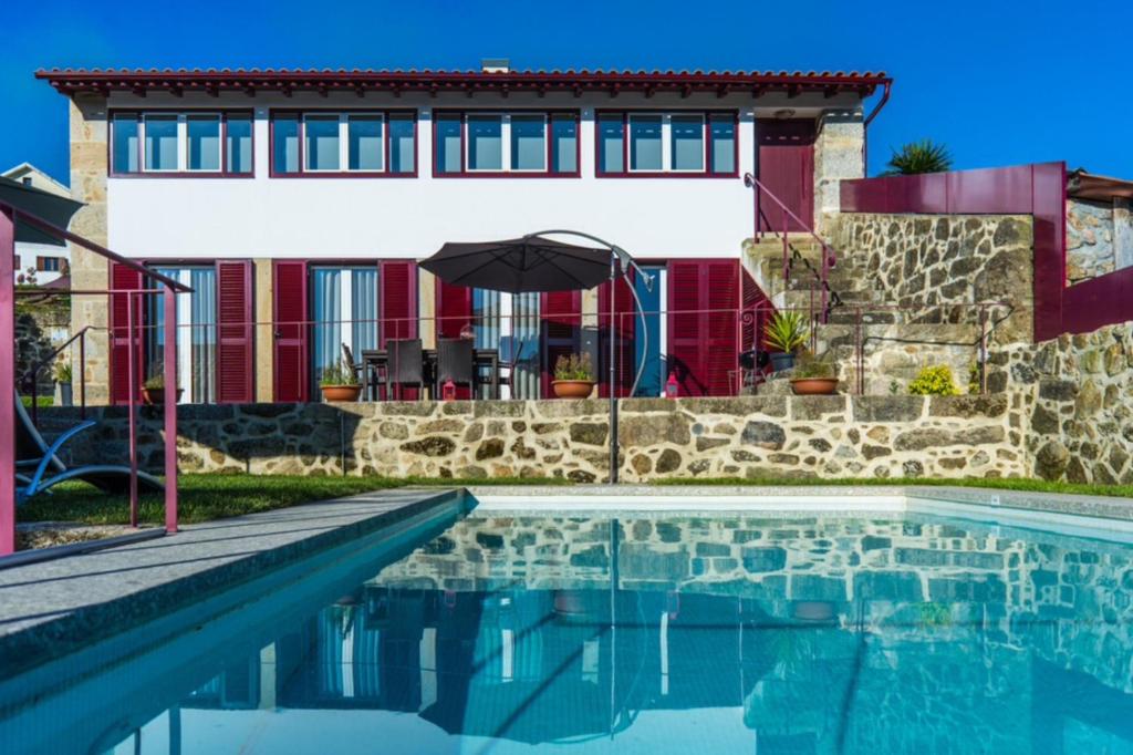 una casa con piscina frente a una casa en Quinta do Cerqueiral, en Arcos de Valdevez